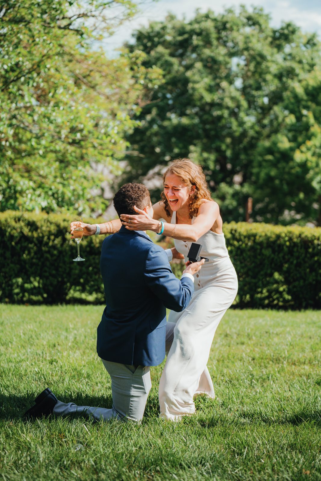 Proposal on a lawn: she lunges in to hug him as he kneels with the ring
