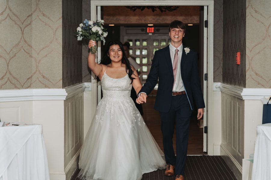 Bride and groom making their grand entrance, her bouquet raised high