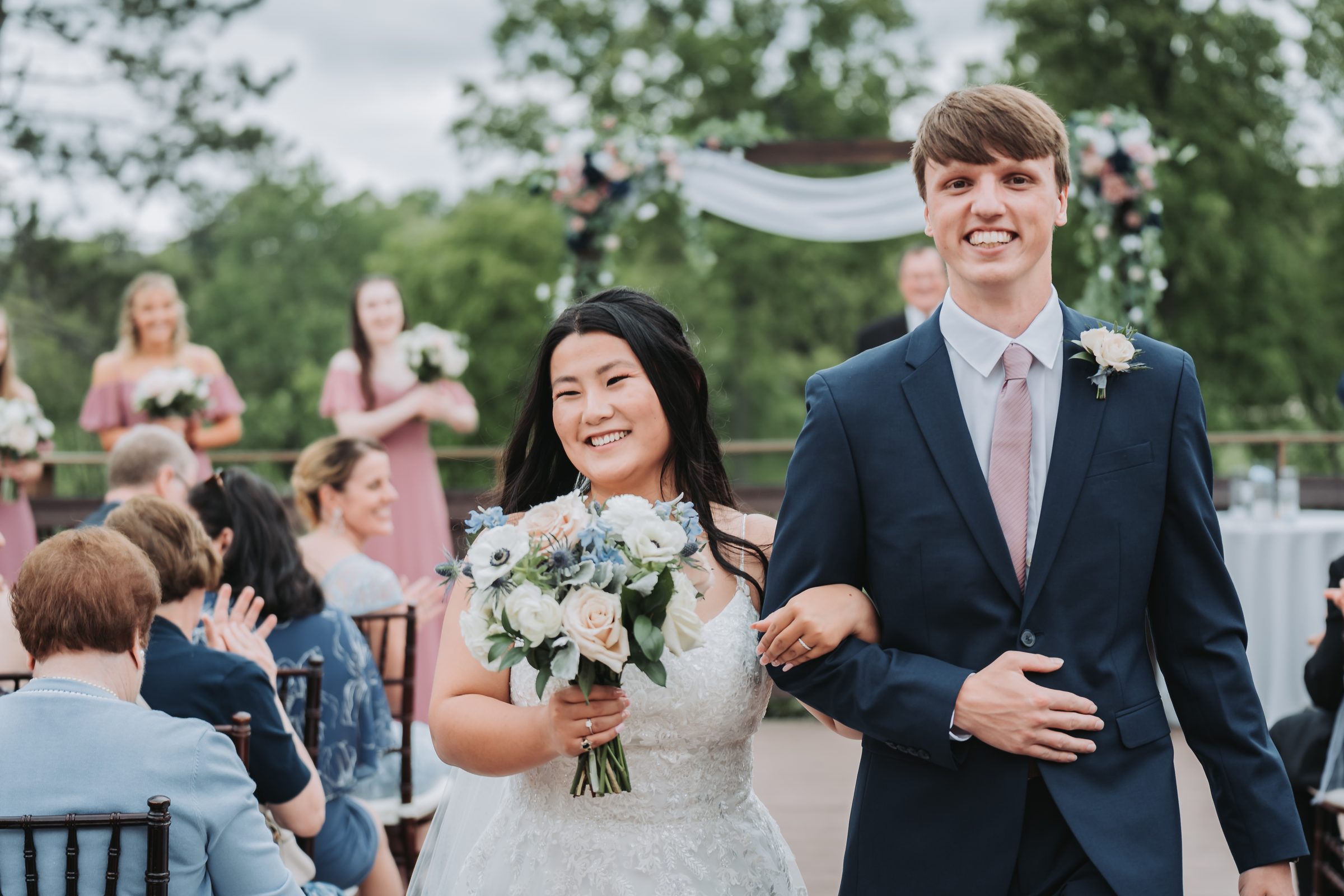 Bride and groom smiling as they walk back down the aisle past their guests