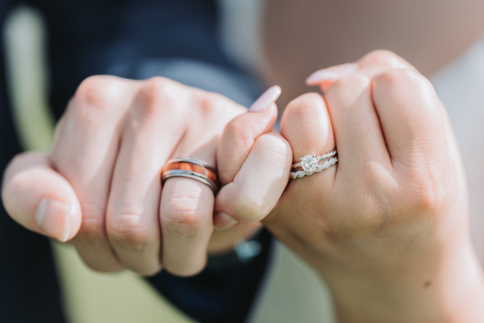 Close-up of the couple's linked pinkies showing their wedding rings