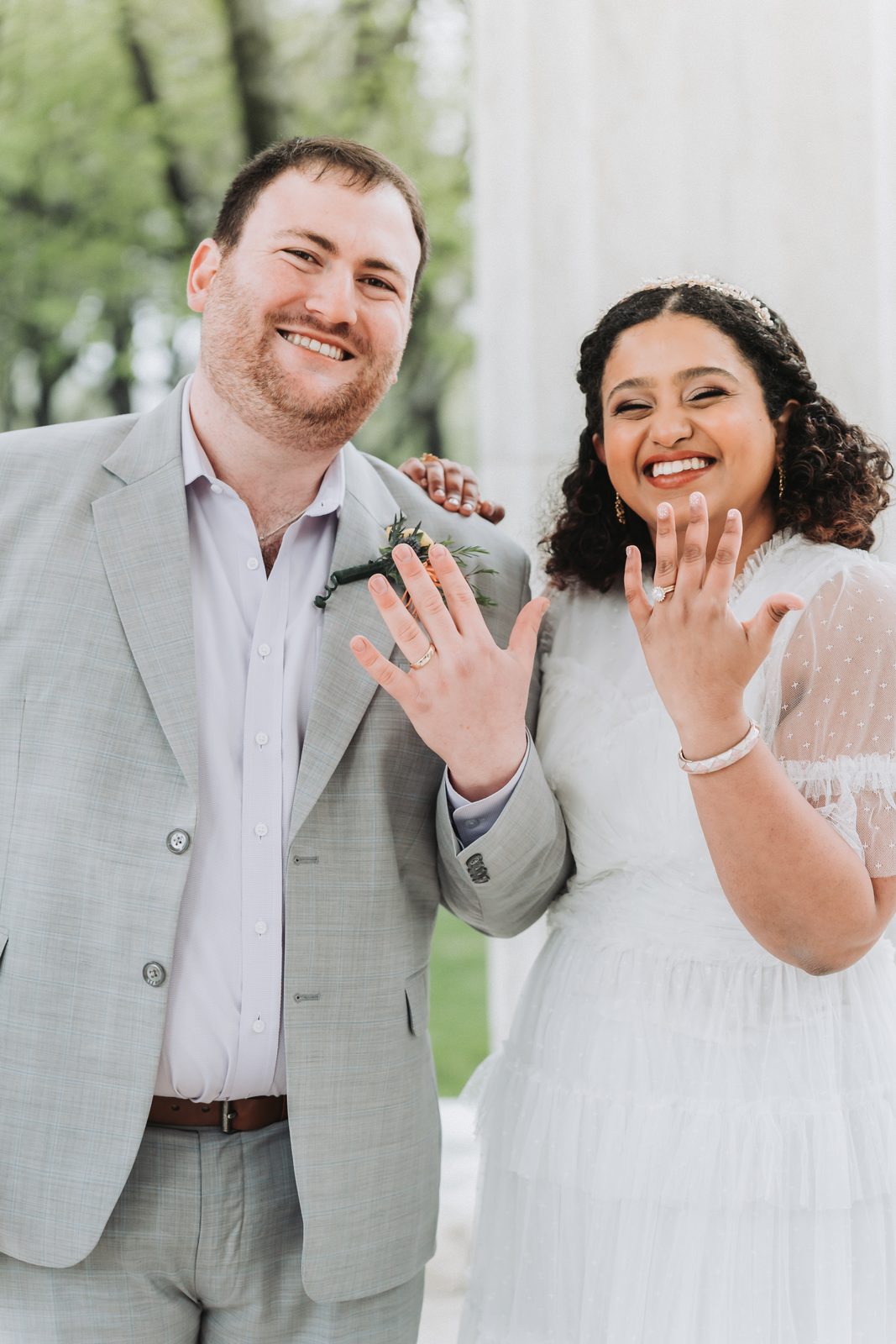 Newlyweds laughing and holding up their hands to show their wedding rings